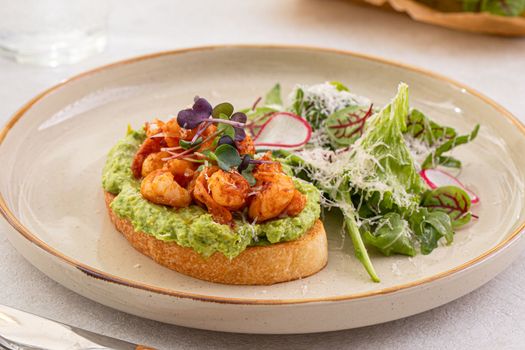 Portion of avocado toast with shrimp and salad