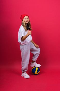 Portrait of a cute eight year old girl in volleyball outfit isolated on a red background