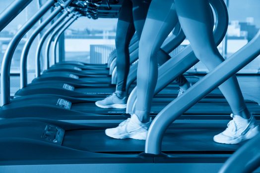 Two young women running on treadmill in gym