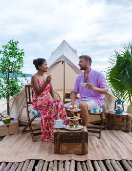 couple having high tea on the beach in front of a tent, men and women afternoon tea at the beach