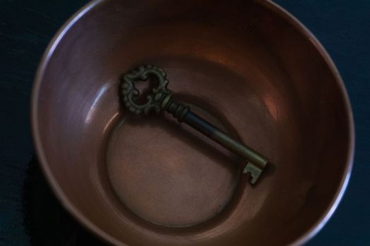 Antique metal key in antique copper bowl