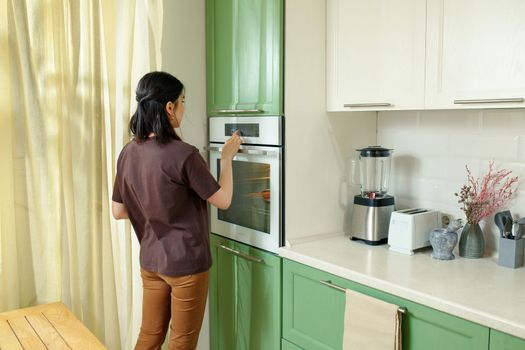 A young woman chooses a baking program that is ergonomically integrated at chest level in the kitchen
