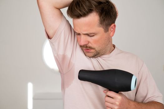 Man with hyperhidrosis sweating very badly under armpit trying to dry with fan