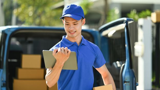 Smiling asian delivery man searching the address on digital tablet. Delivery service, delivery home and shipping concept