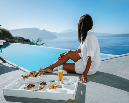 couple on a luxury vacation in Greece, Oia Santorini men and woman having breakfast at the pool