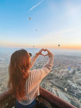 Happy woman during sunrise watching hot air balloons in Cappadocia, Turkey