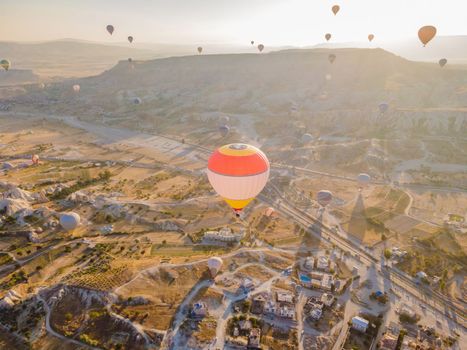 Colorful hot air balloons flying over at fairy chimneys valley in Nevsehir, Goreme, Cappadocia Turkey. Spectacular panoramic drone view of the underground city and ballooning tourism. High quality