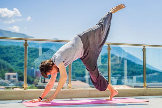Man doing yoga outdoors on a rooftop terrace