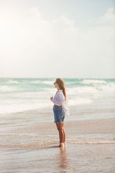 Young happy woman on the beach enjoy her summer vacation. Girl is happy and calm in her stay on the beach