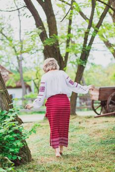 beautiful peasant woman in embroidered clothes walks around the yard