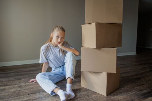 Beautiful young girl moving in new house with cardboard boxes