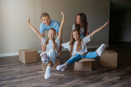 Happy family with two daughters have fun in their new home. Parent with kids enjoy their moving day
