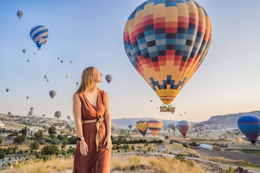 Tourist woman looking at hot air balloons in Cappadocia, Turkey. Happy Travel in Turkey concept. Woman on a mountain top enjoying wonderful view