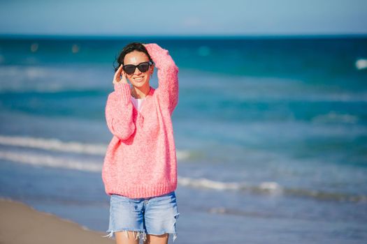Young happy woman in cold windy weather on the beach