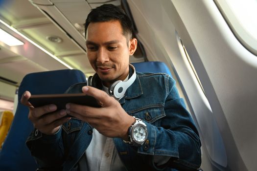 Happy hipster man traveller watching movie or entertainment media on smart phone during flight