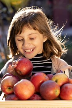 Attractive caucasian girl with apple. Smiling happy child with fresh fruit - emotional portrait close-up. Portrait of healthy girl eating big red apple.