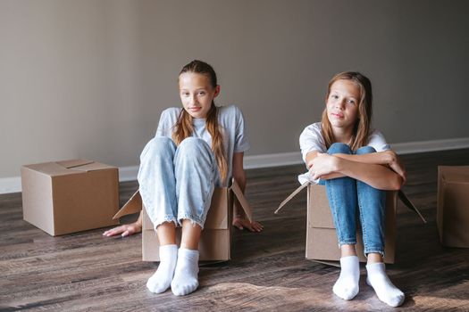 Young teen girls moving in new house with cardboard boxes