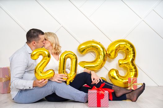 Young couple having romantic date on Christmas eve with 2023 golden foil inflatable balloons.