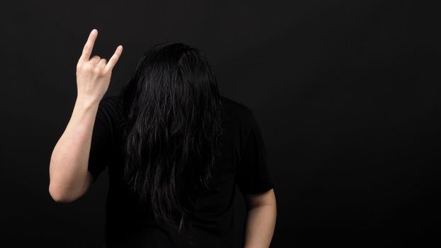 Rocker man long hair and making hand sign of rock