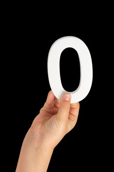 Zero in hand. The number zero is clasped in a hand isolated on a black background. Number zero white in a child's hand on a black background.