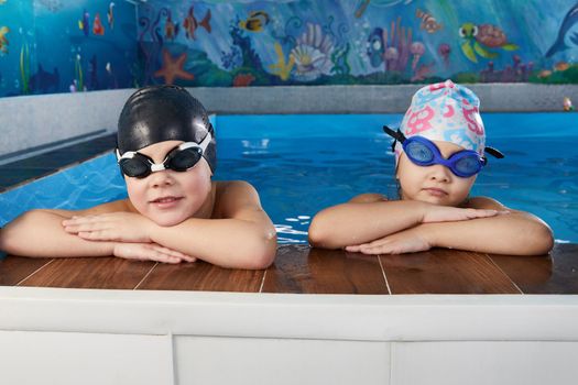 Kids taking a break during swimming class in indoor pool
