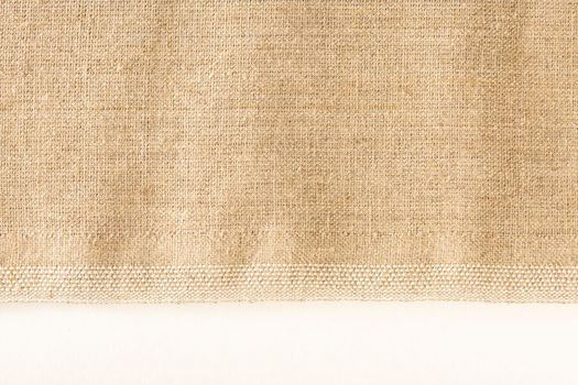 Texture of linen fabric. Natural linen fabric with a finished edge on a white background.