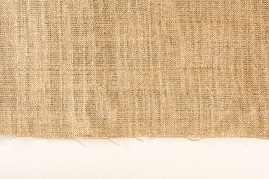 Texture of linen fabric. Natural linen fabric with a raw edge on a white background.