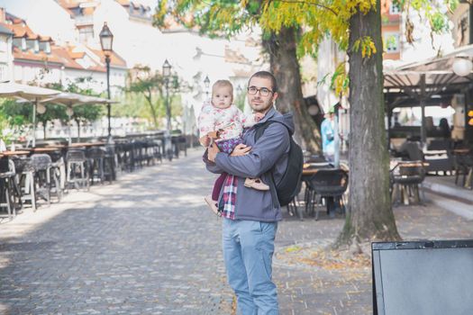 young dad with a charming daughter in his arms in Ljubljana