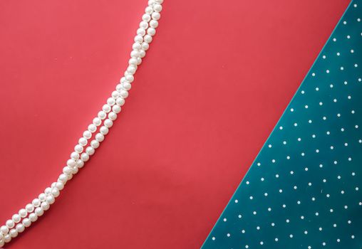 Pearl jewellery necklace and abstract blue polka dot background on coral backdrop