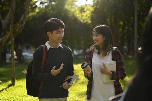 Smiling asian woman university student walking in campus and talking to her friend about exam results