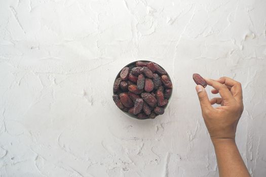 hand pick a dried date fruit from a bowl 