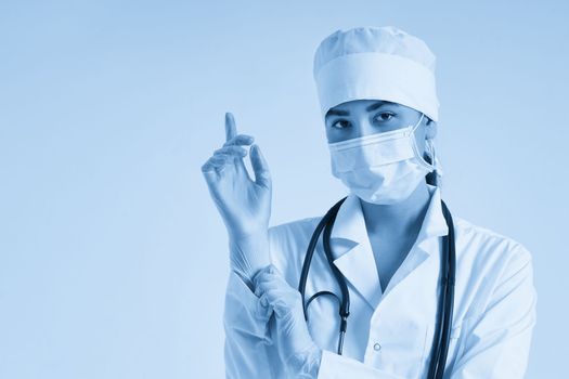 Young doctor putting on surgical gloves over white background