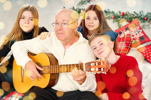Grandfather playing guitar during christmas for grandchildren. Happy man 60s playing guitar christmas songs.
