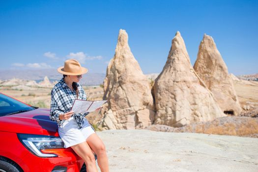 Happy woman with map on car vacation in mountains. Travel by car
