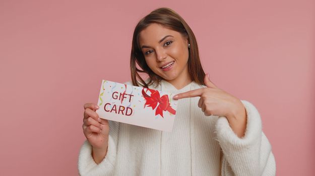 Young woman showing pointing on gift discount certificate voucher coupon for store holidays sale