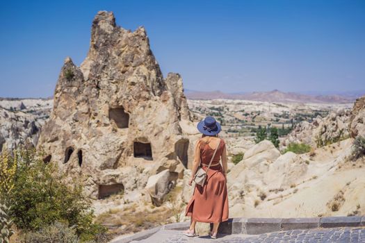 Young woman exploring valley with rock formations and fairy caves near Goreme in Cappadocia Turkey