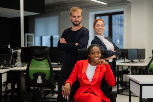 Caucasian redhead woman, bearded caucasian man and african american young woman in office.