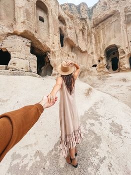 Happy young woman on background of ancient cave formations in Cappadocia, Turkey. The Monastery is one of the largest religious buildings.
