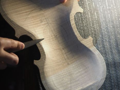 luthier sawing the back belly plate outline of a new handmade violin from above