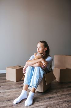 Beautiful young girl moving in new house with cardboard boxes