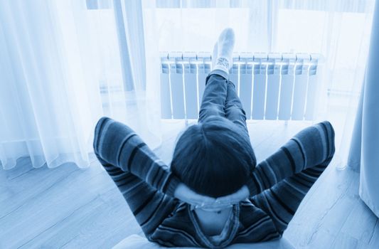 Woman laying on floor with feet raised up on radiator for warming up