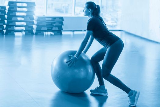 Woman at the gym doing exercises with pilates ball