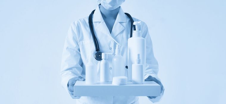 Doctor holding many bottles of hand sanitizers and liquid soap on black background