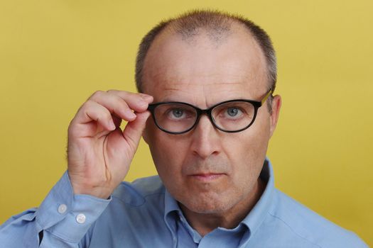 Handsome man with glasses on yellow background.