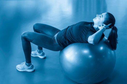 Woman at the gym doing exercises with pilates ball on her back