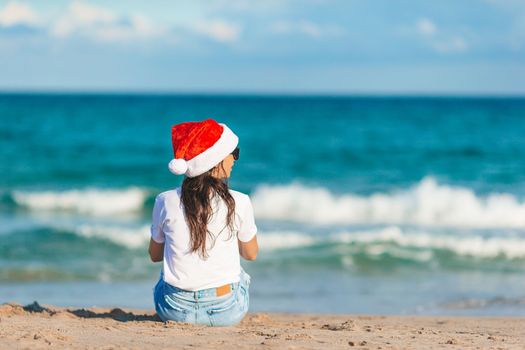 Young woman in Santa hat on Christmas beach holidays