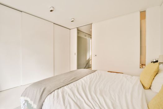 a white bedroom with a large bed and a mirror