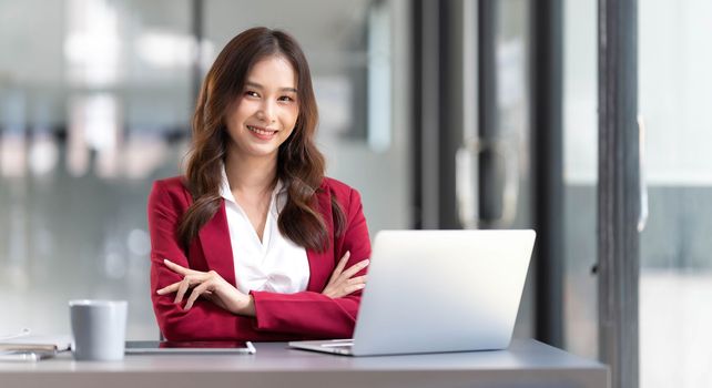 Portrait of smiling beautiful business asian woman in pink suit working in home office desk using computer. Business people employee freelance online marketing e-commerce, work from home concept