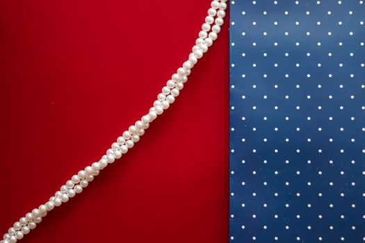 Pearl jewellery necklace and abstract blue polka dot background on red backdrop