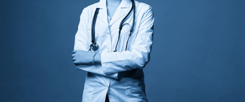Young doctor with stethoscope against dark blue background, studio shot with copy space